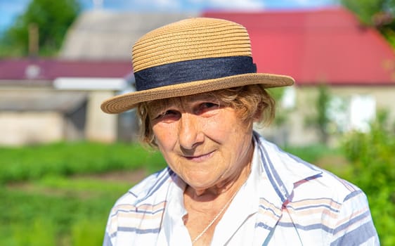 Farmer grandmother in a hat in the garden. Selective focus. People.