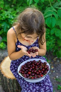 The child eats cherries in the garden. Selective focus. Food.