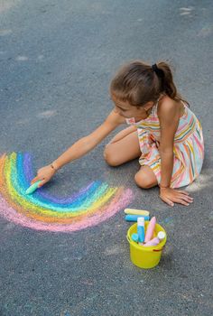 Children paint a rainbow on the asphalt. Selective focus. Kids.