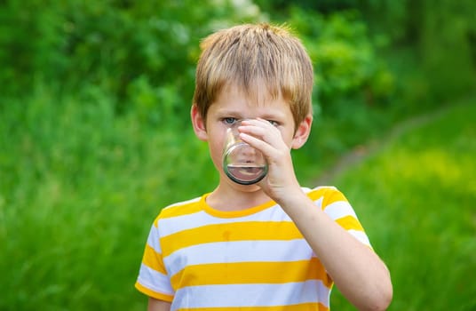 Child boy drinks water from a glass. Selective focus. Kid.