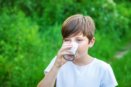 Child boy drinks water from a glass. Selective focus. Kid.