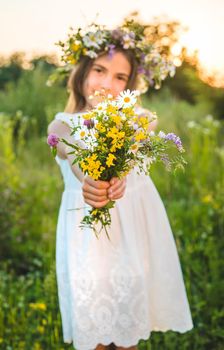 Child girl with wildflowers in summer. Selective focus. Nature.