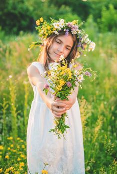 Child girl with wildflowers in summer. Selective focus. Nature.