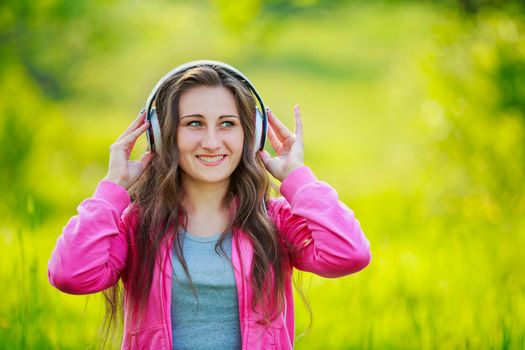 girl listening to music with headphones sitting in nature