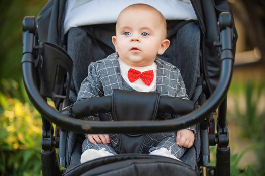 little boy sitting in a stroller for a walk