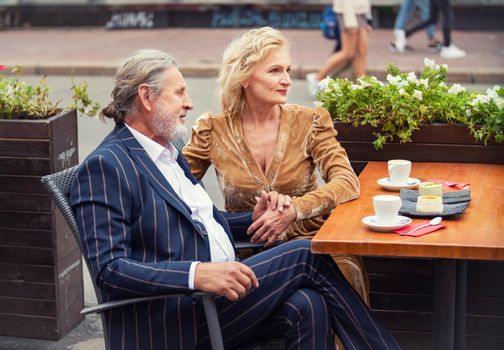 elderly couple sitting at a table on the street