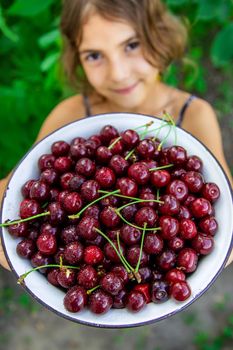 The child eats cherries in the garden. Selective focus. Food.