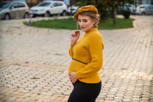 pregnant woman in a yellow sweater on the background of the city