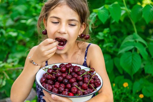 The child eats cherries in the garden. Selective focus. Food.