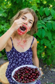 The child eats cherries in the garden. Selective focus. Food.