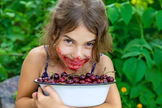 The child eats cherries in the garden. Selective focus. Food.