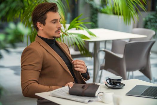 a man in a business suit sits at a table and smokes