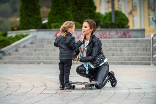 mom with daughter and skate on the background of the city