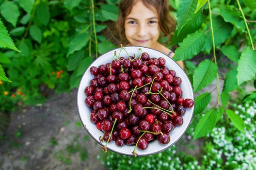 The child eats cherries in the garden. Selective focus. Food.