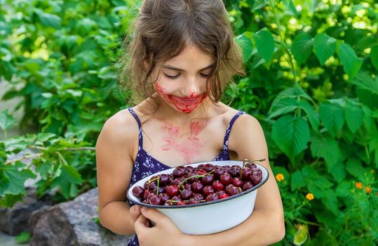 The child eats cherries in the garden. Selective focus. Food.