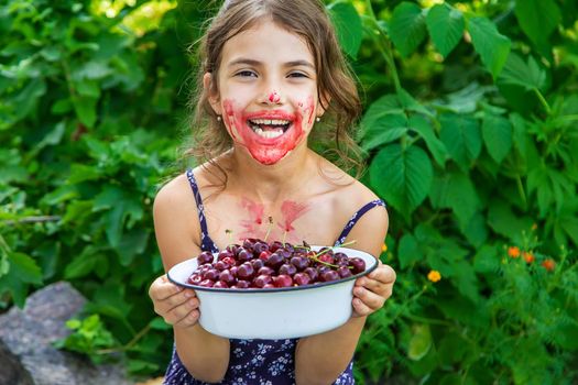 The child eats cherries in the garden. Selective focus. Food.