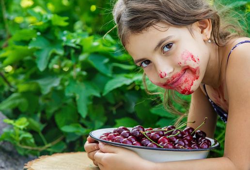 The child eats cherries in the garden. Selective focus. Food.