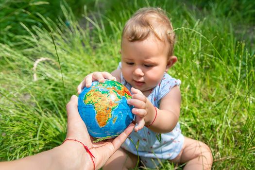 The child holds the globe in his hands. Selective focus. Nature.