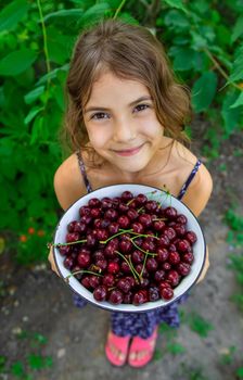 The child eats cherries in the garden. Selective focus. Food.