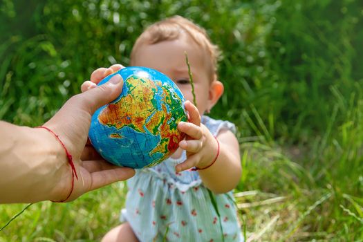 The child holds the globe in his hands. Selective focus. Nature.