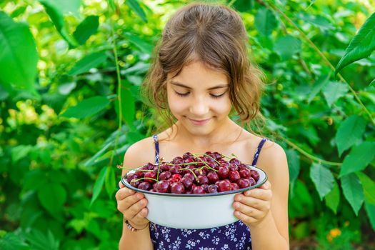The child eats cherries in the garden. Selective focus. Food.