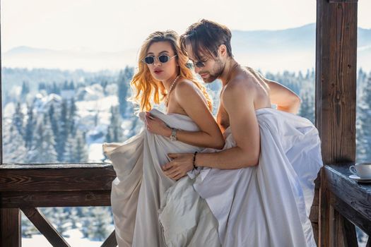 couple in winter in blankets on the background of mountains