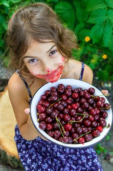 The child eats cherries in the garden. Selective focus. Food.