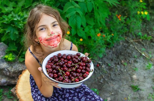 The child eats cherries in the garden. Selective focus. Food.