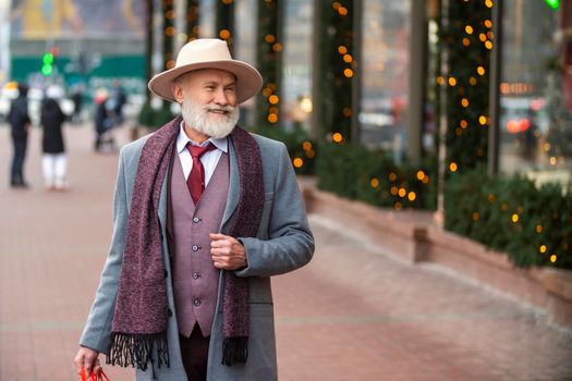 bearded grandfather with a handbag walks on the street