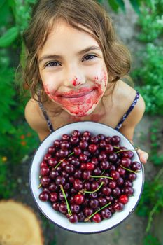 The child eats cherries in the garden. Selective focus. Food.