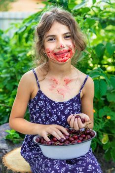 The child eats cherries in the garden. Selective focus. Food.