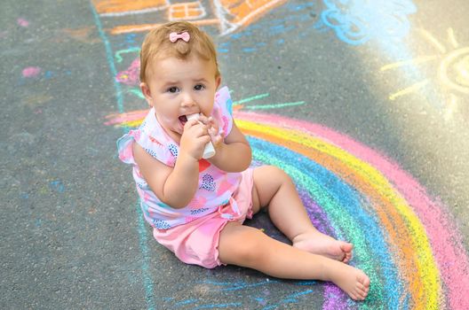 Baby eats chalk for drawing. Selective focus. Kids.