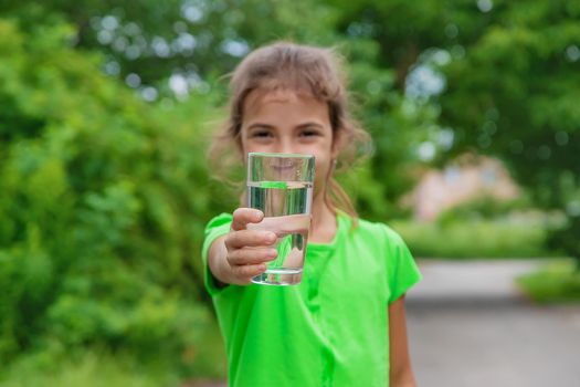 Child girl drinks water from a glass. Selective focus. Kid.