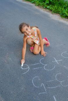 The child is doing chalk lessons on the asphalt. Selective focus. Kid.