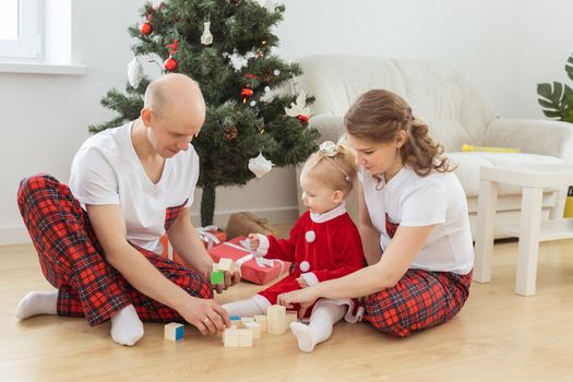 Baby child with hearing aid and cochlear implant having fun with parents in christmas room. Deaf and health