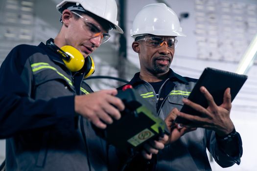 Group of factory job workers using adept machine equipment in a workshop . Industry manufacturing and engineering technology concept .