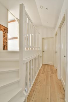 White hallway with wooden stairway leading to second floor of modern luxury apartment with minimalist interior design