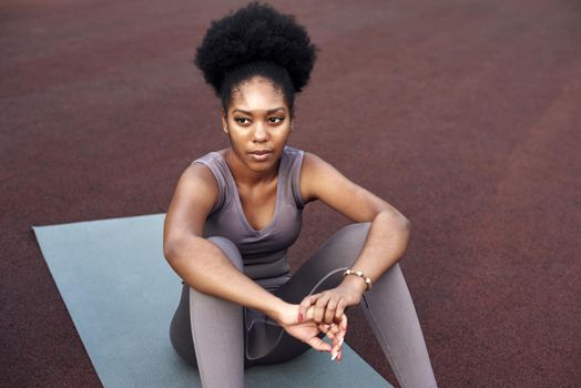 African American woman in sportswear is resting in the stadium after running or training. Fitness woman exercising outdoors