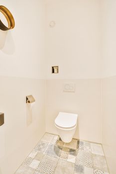 Wall hung toilet and small sink in corner in lavatory room with beige tile