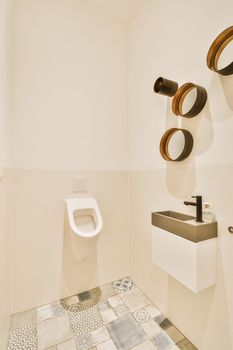 Wall hung toilet and small sink in corner in lavatory room with beige tile