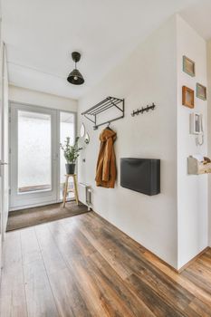 Hallway with coat hooks, doormat and white walls in bright apartment