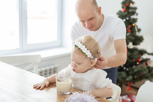 Father helps to put on cochlear implant for his deaf baby daughter in christmas living room copy space. Hearing aid and innovating medical technologies treatment deafness