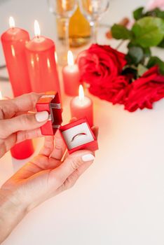 woman hand holding wedding ring in red box