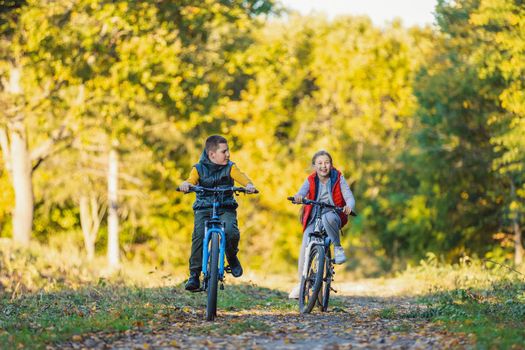 happy kids ride a bike in the autumn forest