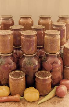 In glass jars Lecho of canned bell peppers and tomatoes, adjika, canned tomatoes, near fresh peppers and tomatoes