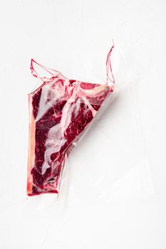 T-bone or florentine dry aged raw marbled beef steak in vacuum packaging set, on white stone background, top view flat lay