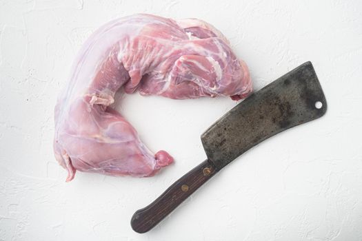 Fresh raw rabbit meat set, and old butcher cleaver knife, on white stone background