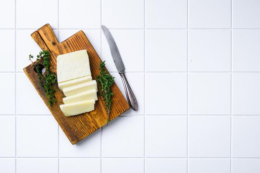 Halloumi Cheese fresh cut, on white ceramic squared tile table background, top view flat lay, with copy space for text