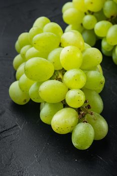 Red and white grapes set, green fruits, on black stone background