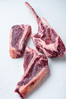 Raw prime beef meat dry aged steak set, tomahawk, t bone or porterhouse and club steak, on white stone background